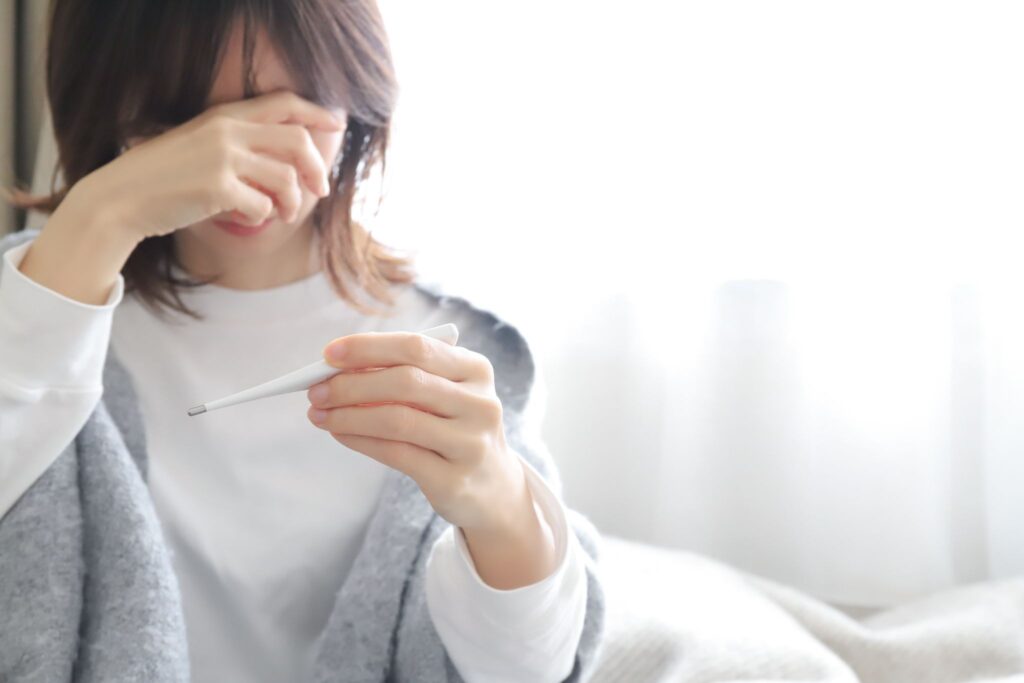 体温計を見ておでこを押さえている女性