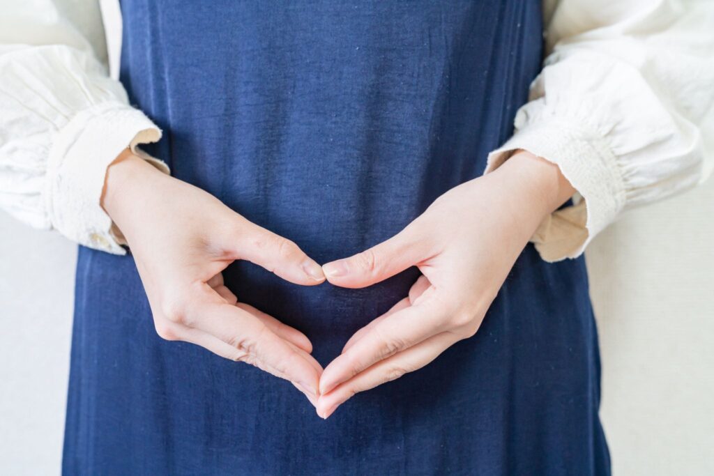 お腹の前で手でハートマークを作る妊婦