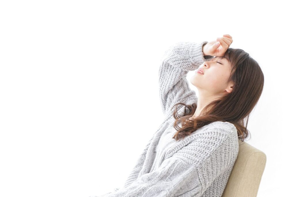 椅子に座りおでこに手を当てて天井を仰いでいる女性