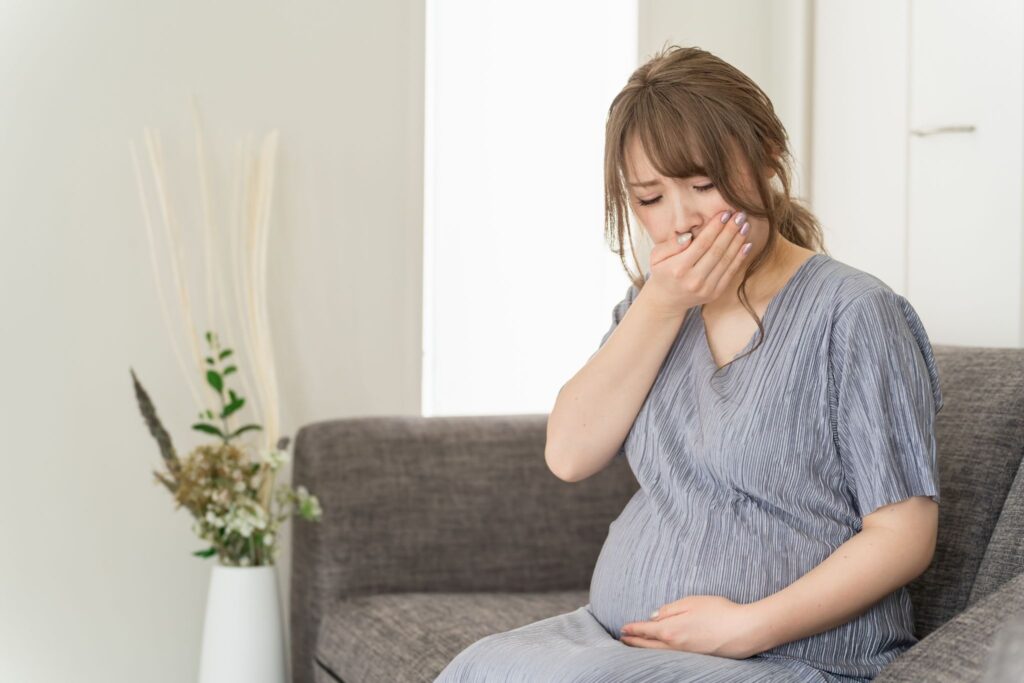 つわりで口元を押さえている妊婦