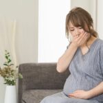 つわりで口元を押さえている妊婦