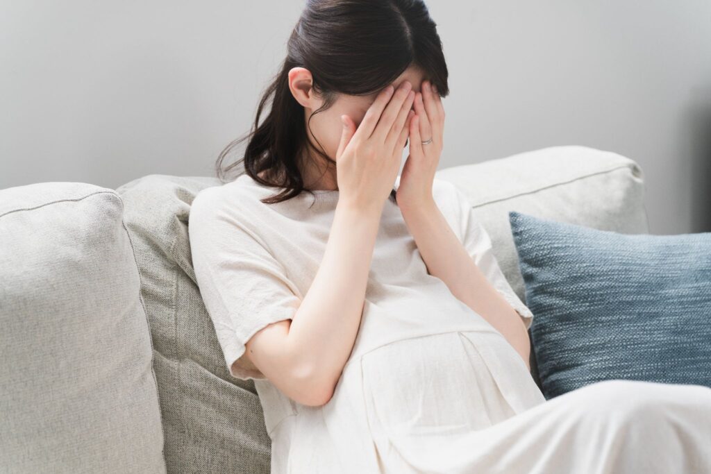 つわりがつらくて顔を覆っている妊婦
