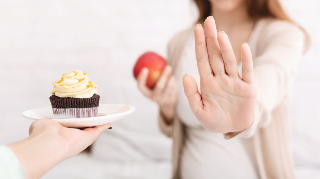 ケーキを差し出す手を拒否している妊婦