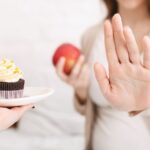 ケーキを差し出す手を拒否している妊婦