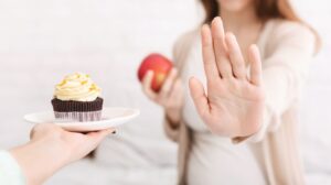 ケーキを差し出す手を拒否している妊婦