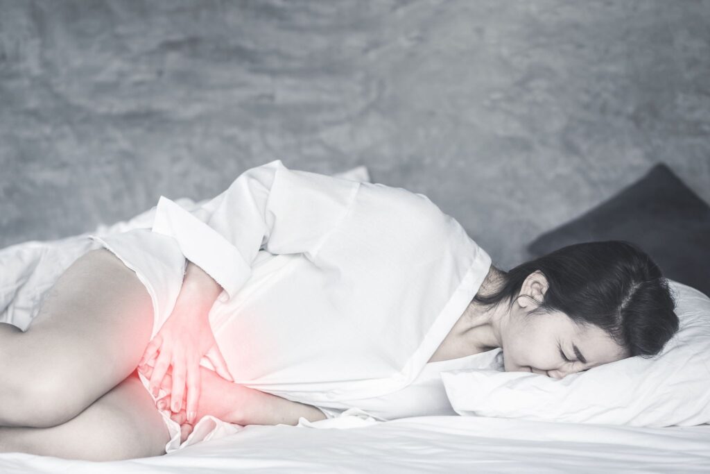 お腹を押さえてベッドに横になっている女性