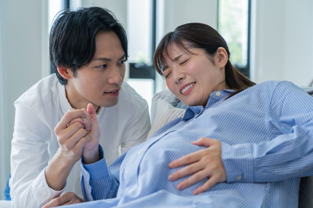 陣痛がきてつらそうな妊婦とその手を握る夫