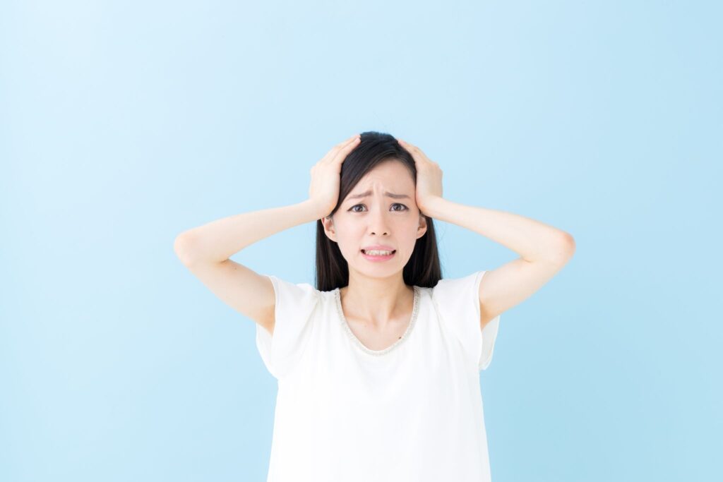 ピルを飲み忘れてしまい頭を押さえている女性