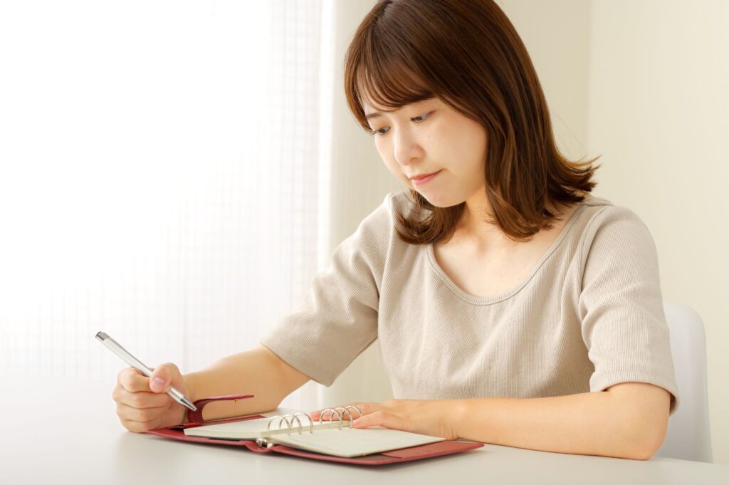 ピル服用中の生理はいつくるのか考えている女性。手帳をチェックしている