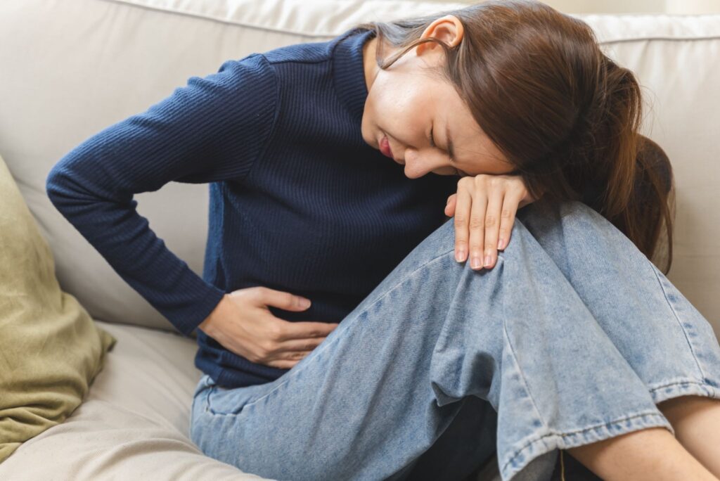 お腹を押さえてつらそうにしている女性