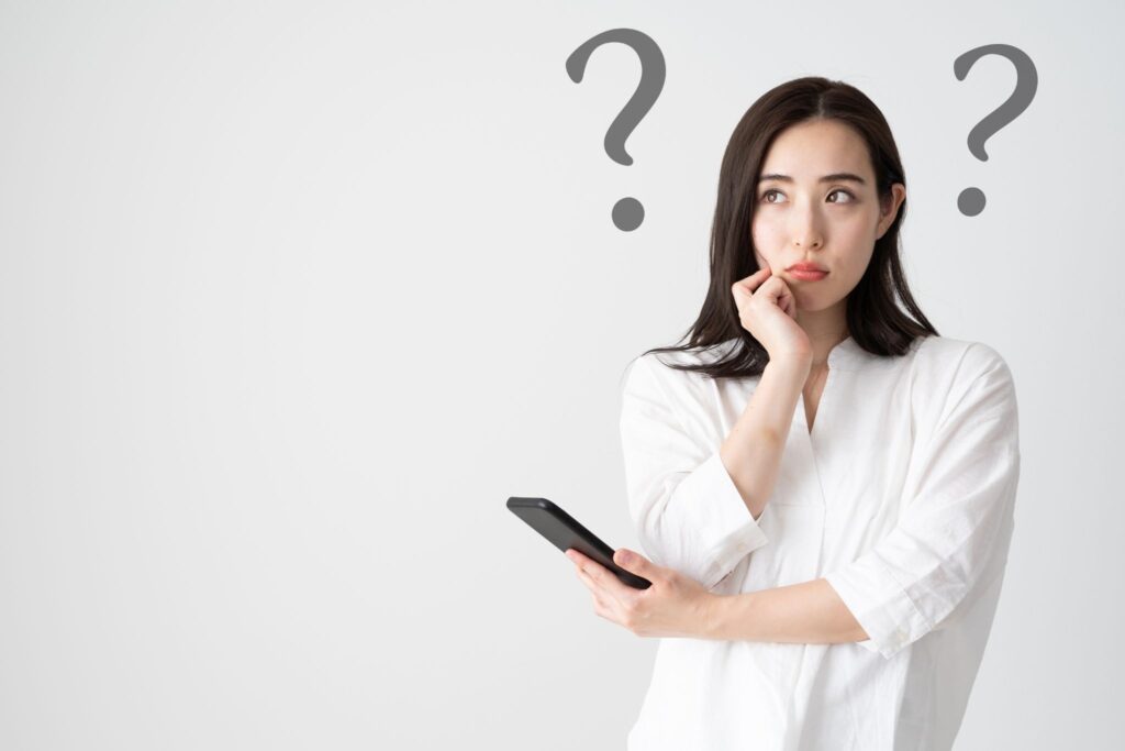スマホを持って何かを考えている女性とはてなマーク