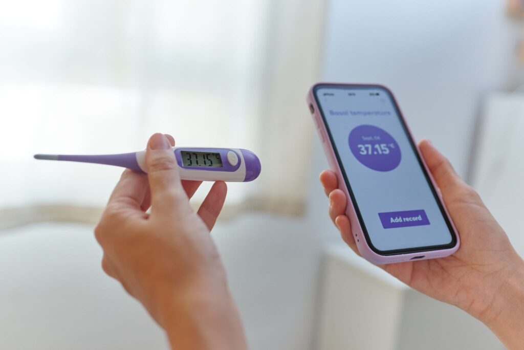 スマホと体温計を持っている女性