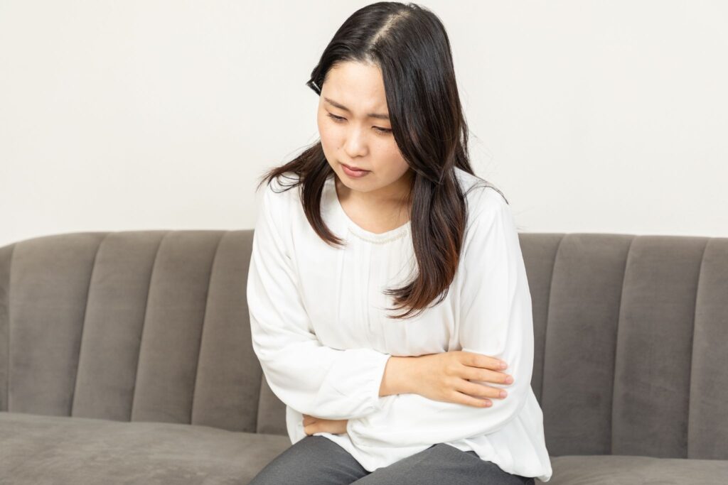 お腹を押さえて前かがみになっている女性