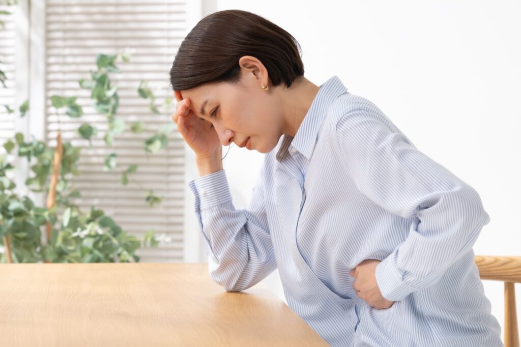 お腹を押さえて前かがみになっている女性
