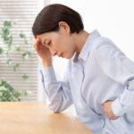 お腹を押さえて前かがみになっている女性