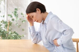 お腹を押さえて前かがみになっている女性