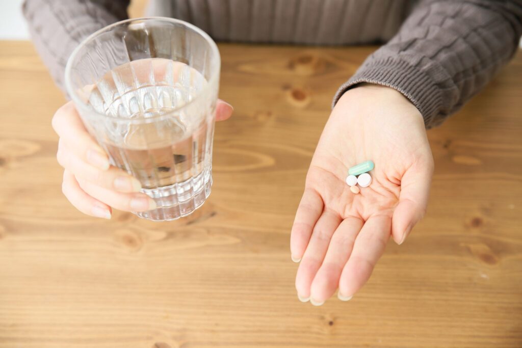 薬を飲もうとして手のひらに乗せている女性