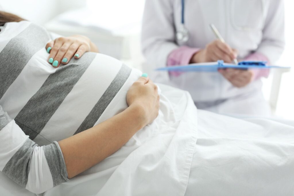 ベッドに横になって医師と話していている妊婦