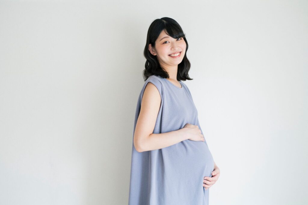 お腹に触れて笑顔の妊婦