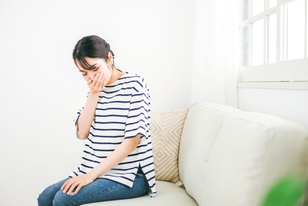 ソファに座って口元を押さえる女性