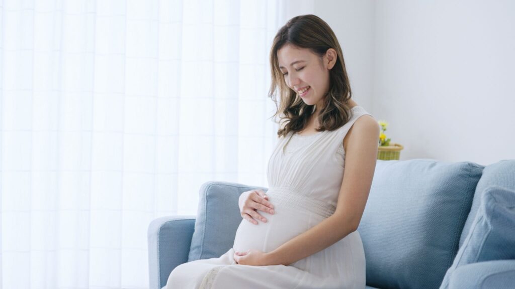 笑顔でお腹に触れている妊婦