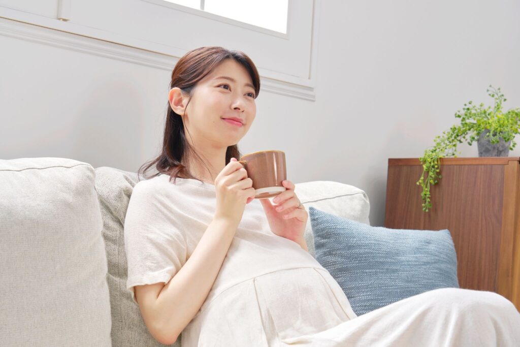 リラックスして飲み物を飲んでいる妊婦