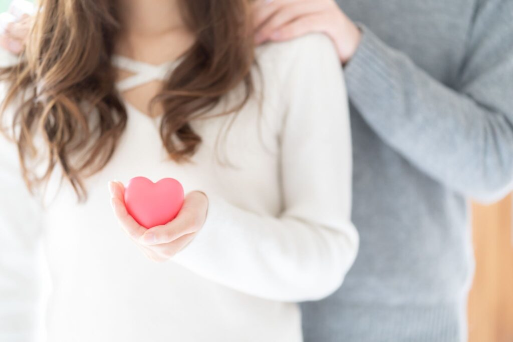 ハートを持つ女性と肩に触れている夫