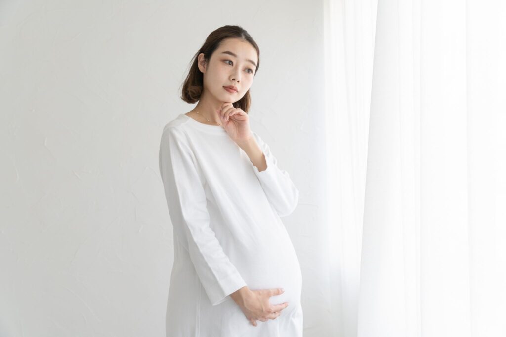 お腹に触れて首を傾げている妊婦