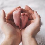 新生児の足を両手で包みこんでいる