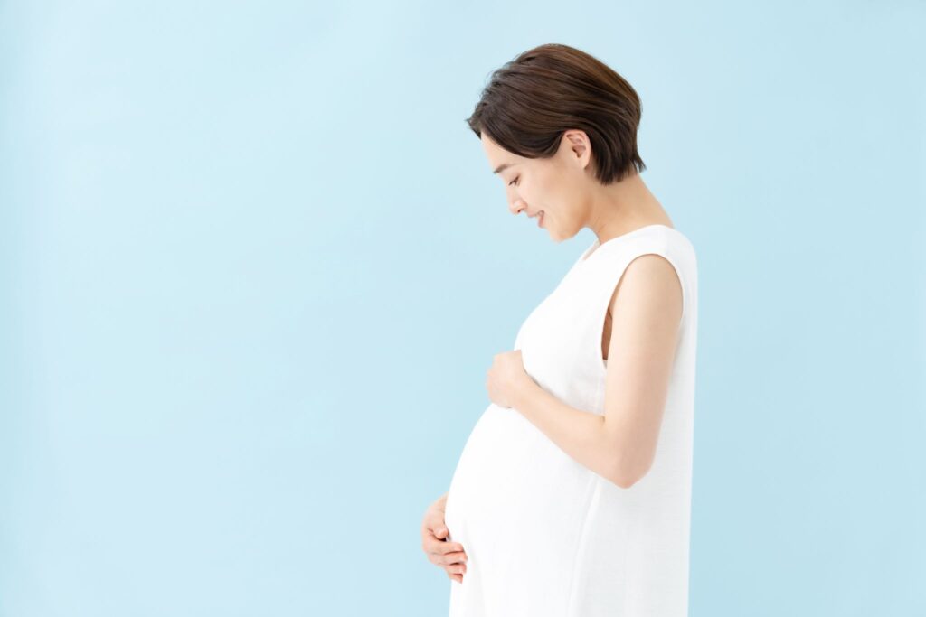 お腹に触れて笑顔の妊婦