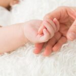 大人の手を握る新生児