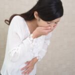 つわりで口元を押さえる女性