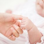 大人の手を握る新生児